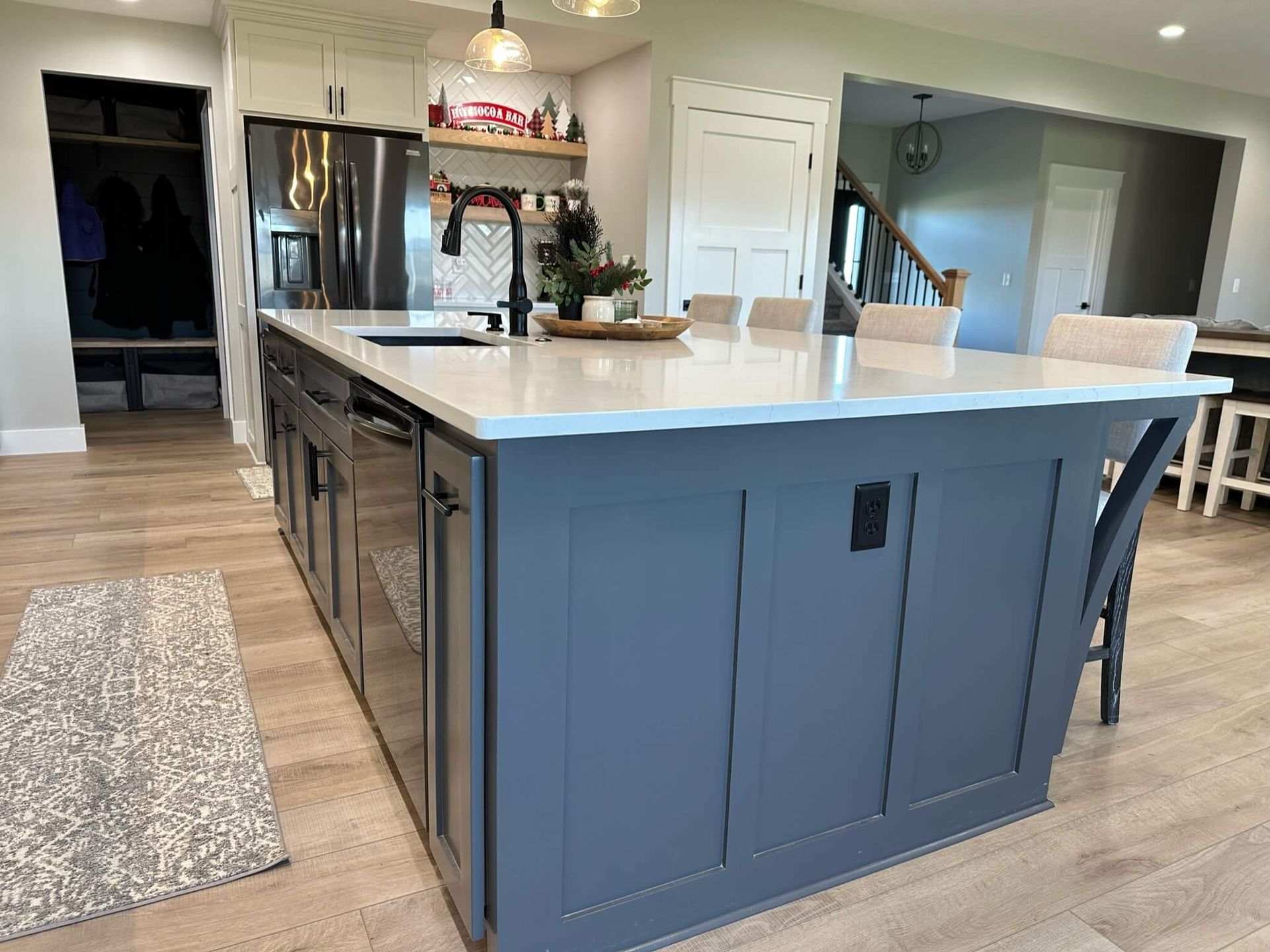 A large, dark blue kitchen island with a white countertop and seating, situated in a modern, open-concept home.