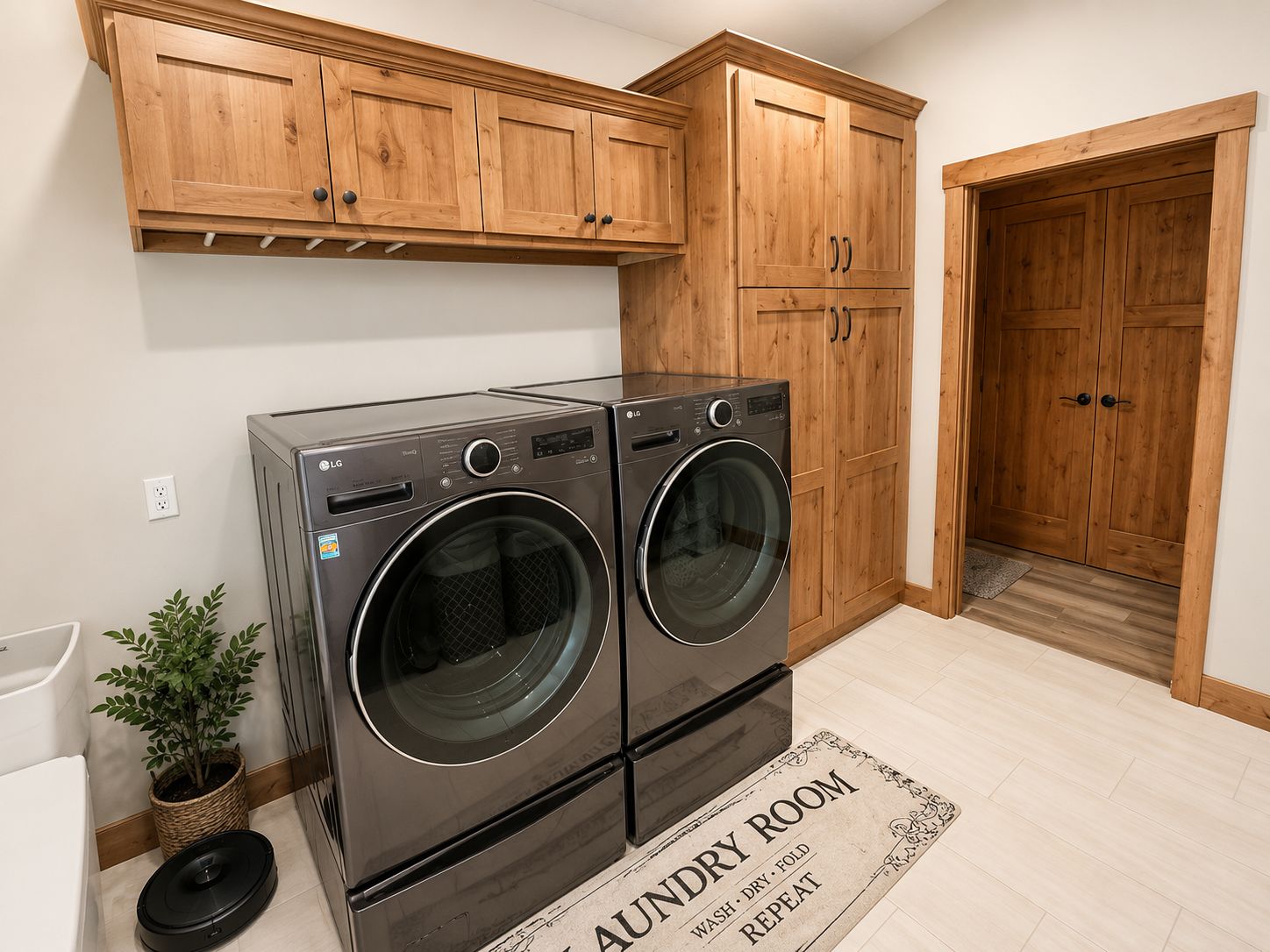A laundry room with dark grey front-loading machines, and wooden cabinets