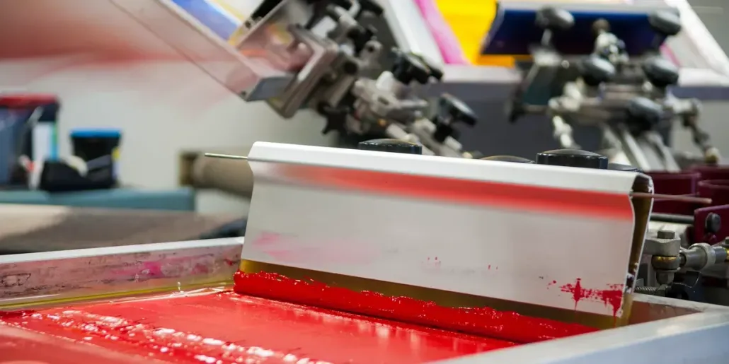 Blue and yellow screen printing machine with multiple arms and stations.
