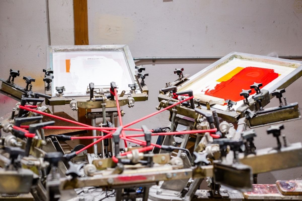 Screen printing machine with red and orange ink on screens.