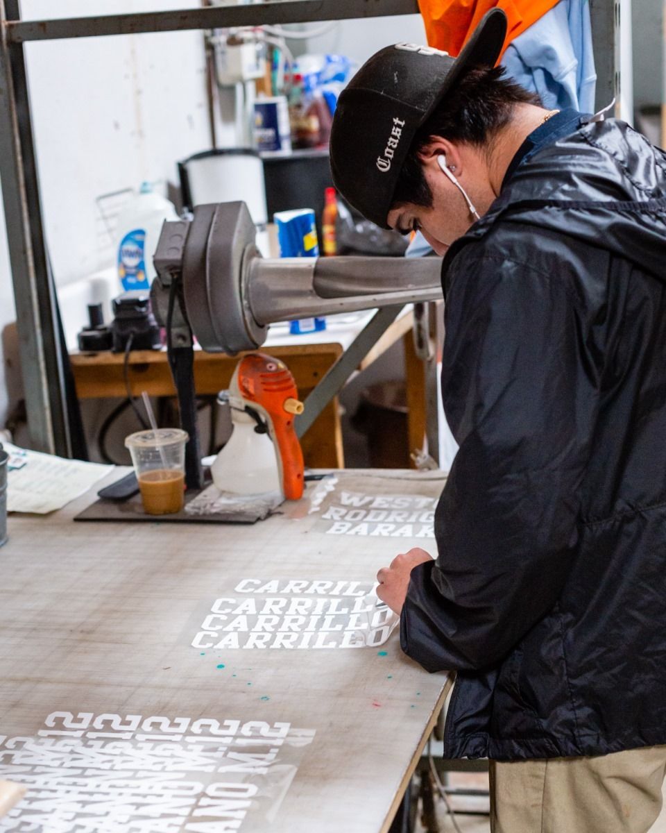 Person in a cap and jacket inspecting stencils on a table. Workspace.