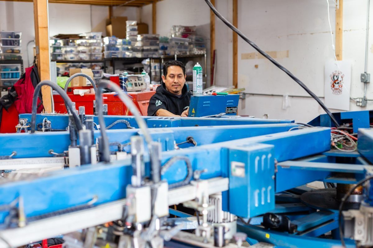 Man working at blue screen printing machine in a workshop.