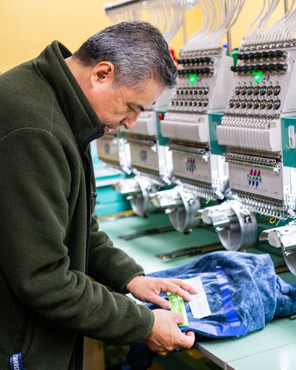 Man inspects garment on embroidery machine.
