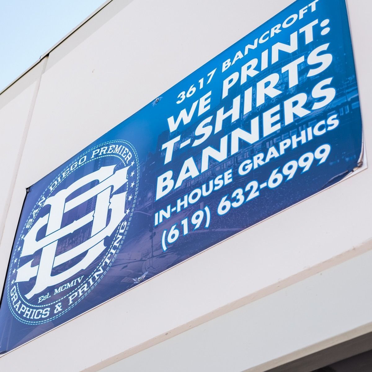 Sign for San Diego Premier Graphics & Printing: Offers t-shirts, banners. White and blue, with phone number (619) 632-6999.
