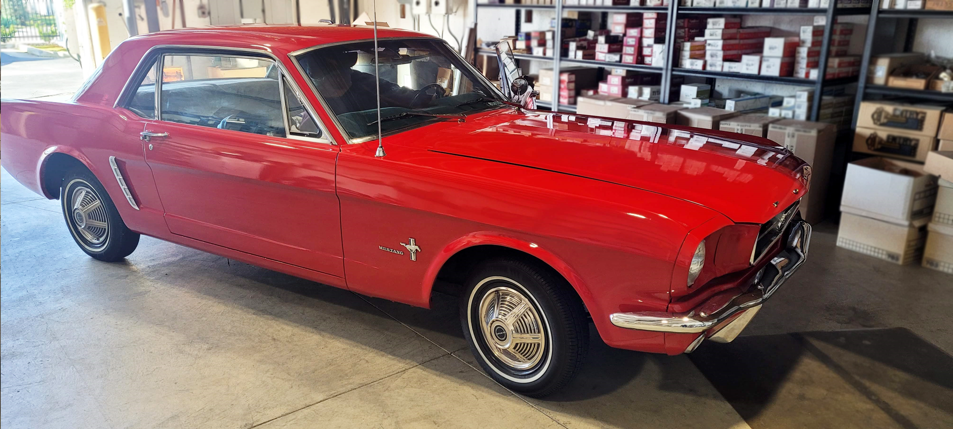 A red mustang is parked in a garage.