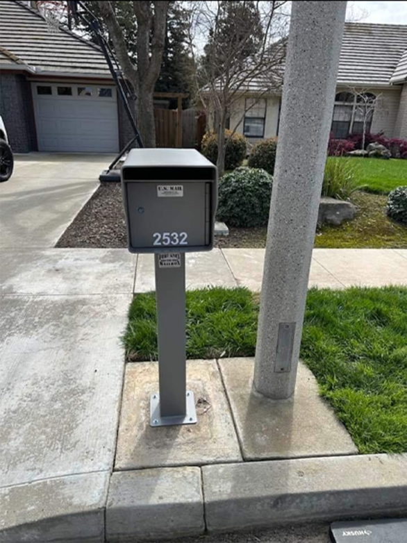 A mailbox with the address 2532 is on the sidewalk in front of a house.
