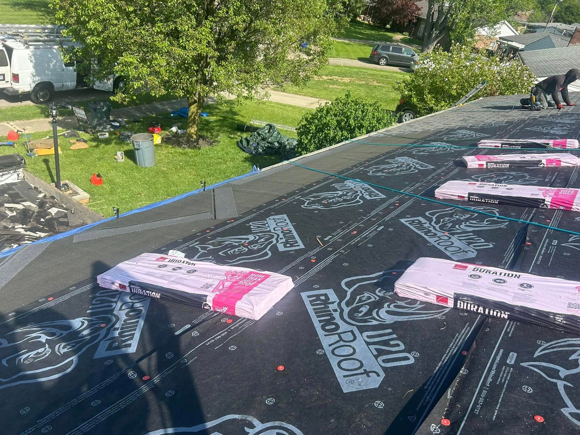Roofing work in progress with RhinoRoof underlayment covering a sloped roof, viewed from above.