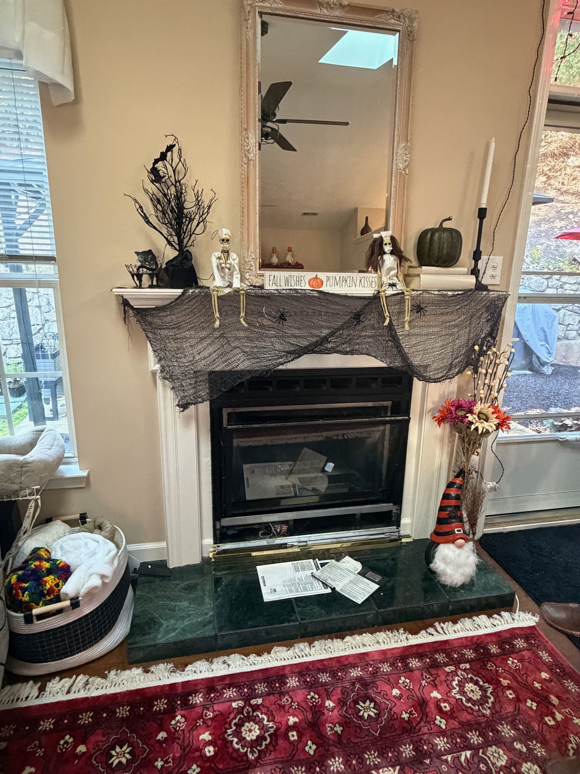 Decorated living room fireplace with mirror, mantle garland, greenery, and red patterned rug