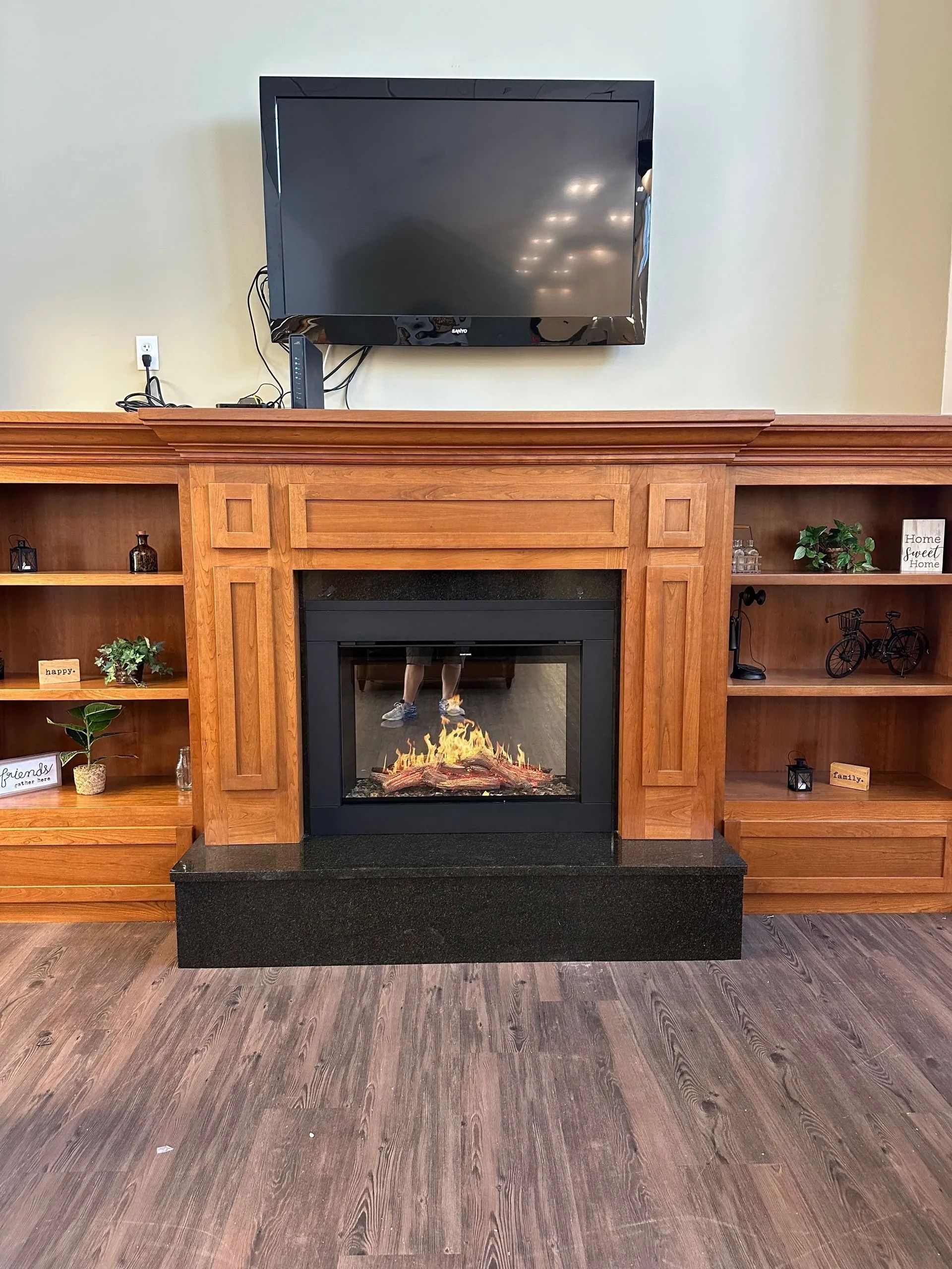 Fireplace with TV mounted above, flanked by bookshelves, set on wood-look flooring.