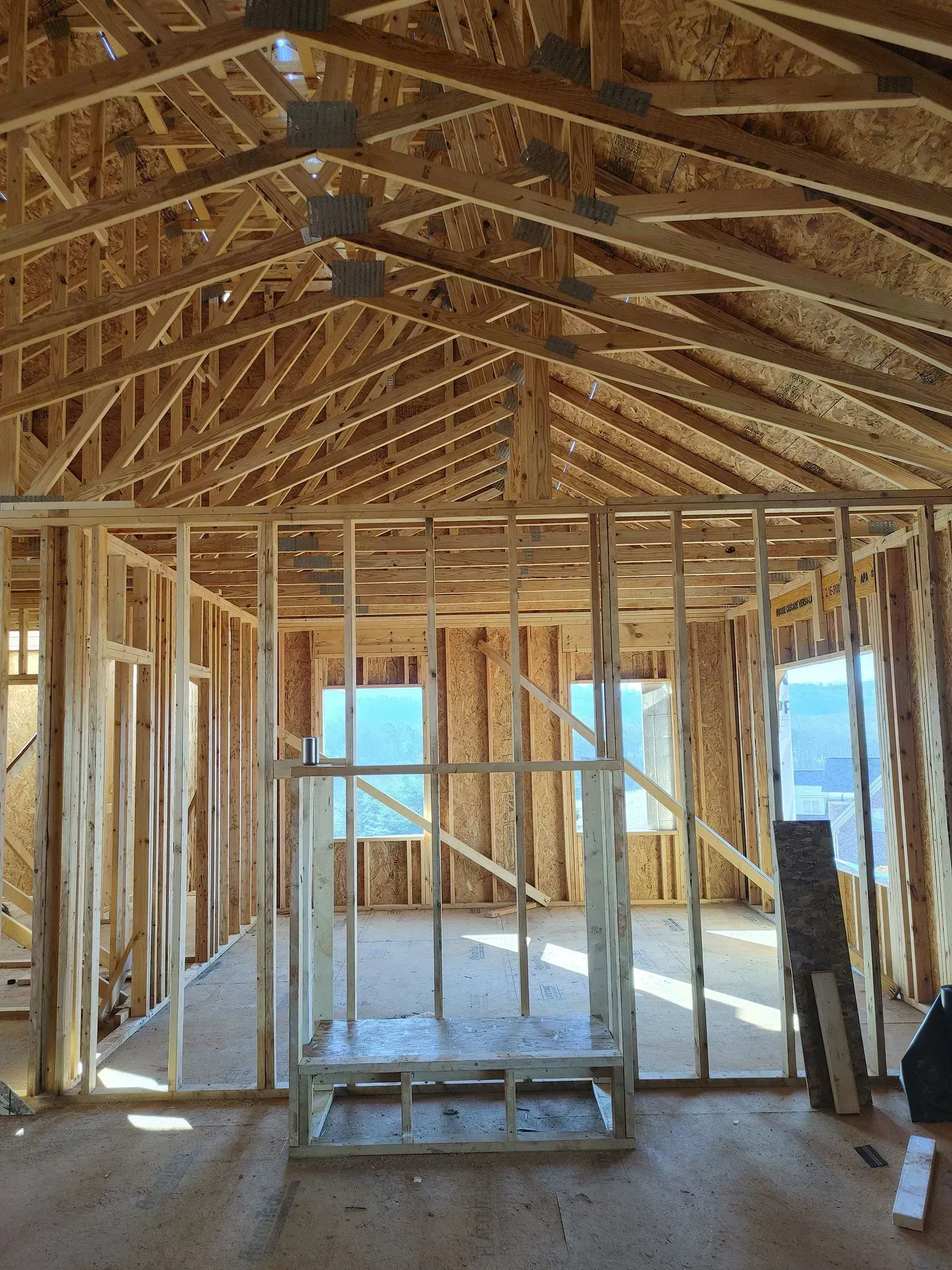 Interior view of a building under construction, showing wooden framing for walls, roof, and windows.