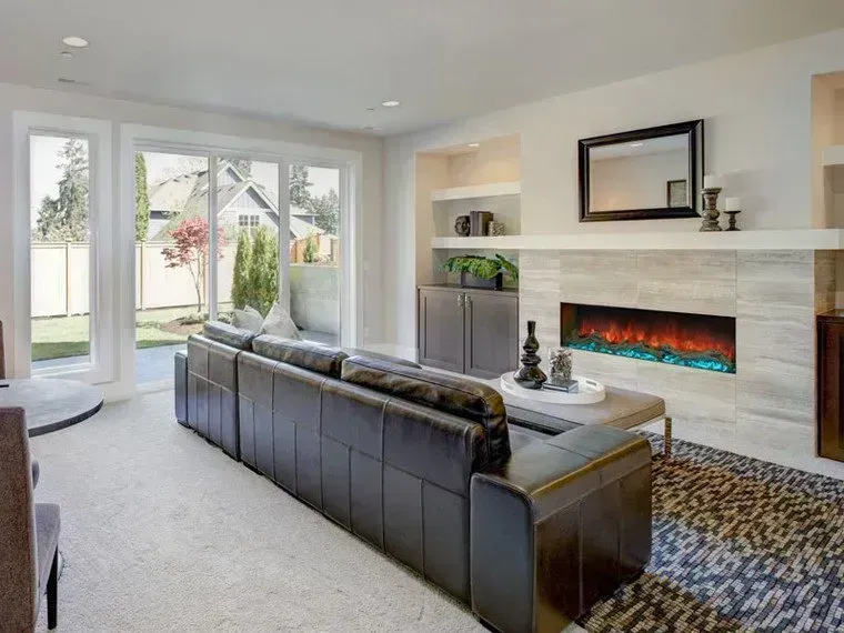 Living room with black leather sofa, fireplace, and sliding glass doors to a backyard.
