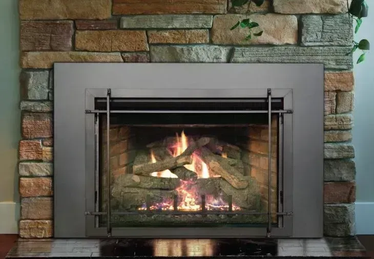 Fireplace with burning logs, inside a stone surround.