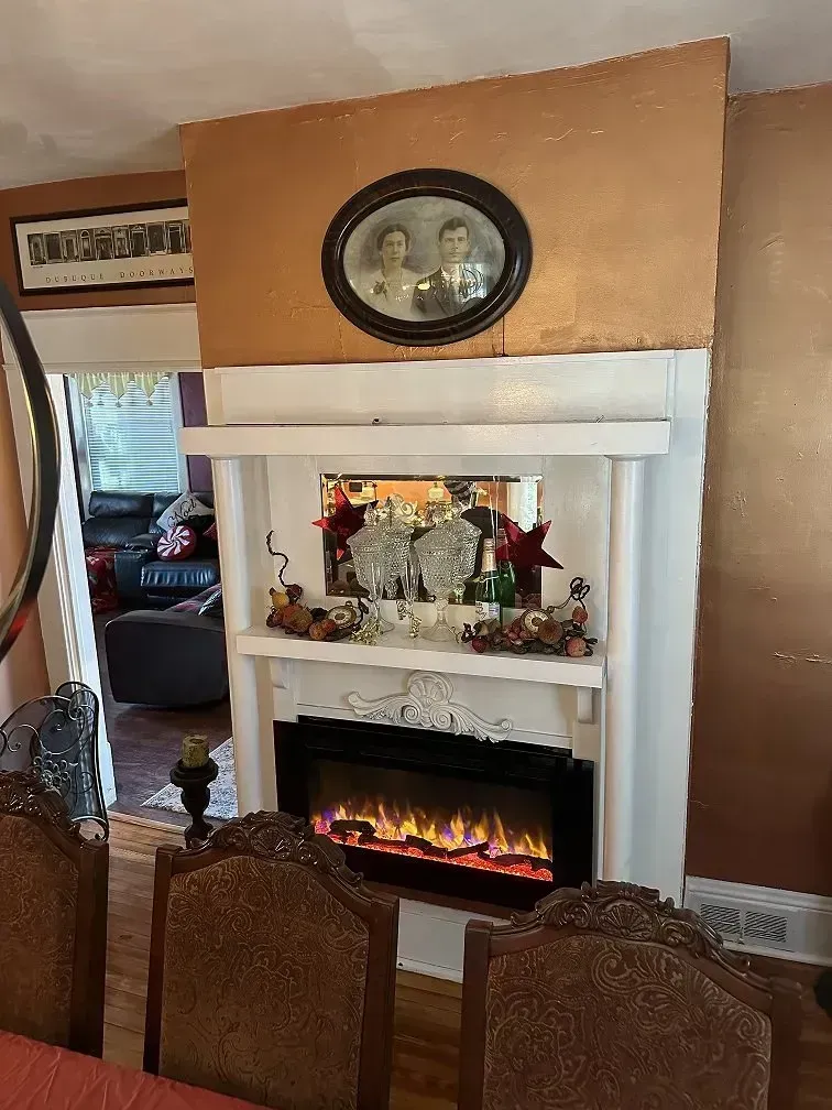 Fireplace with a glowing electric fire, decorated with vases and a framed photo.