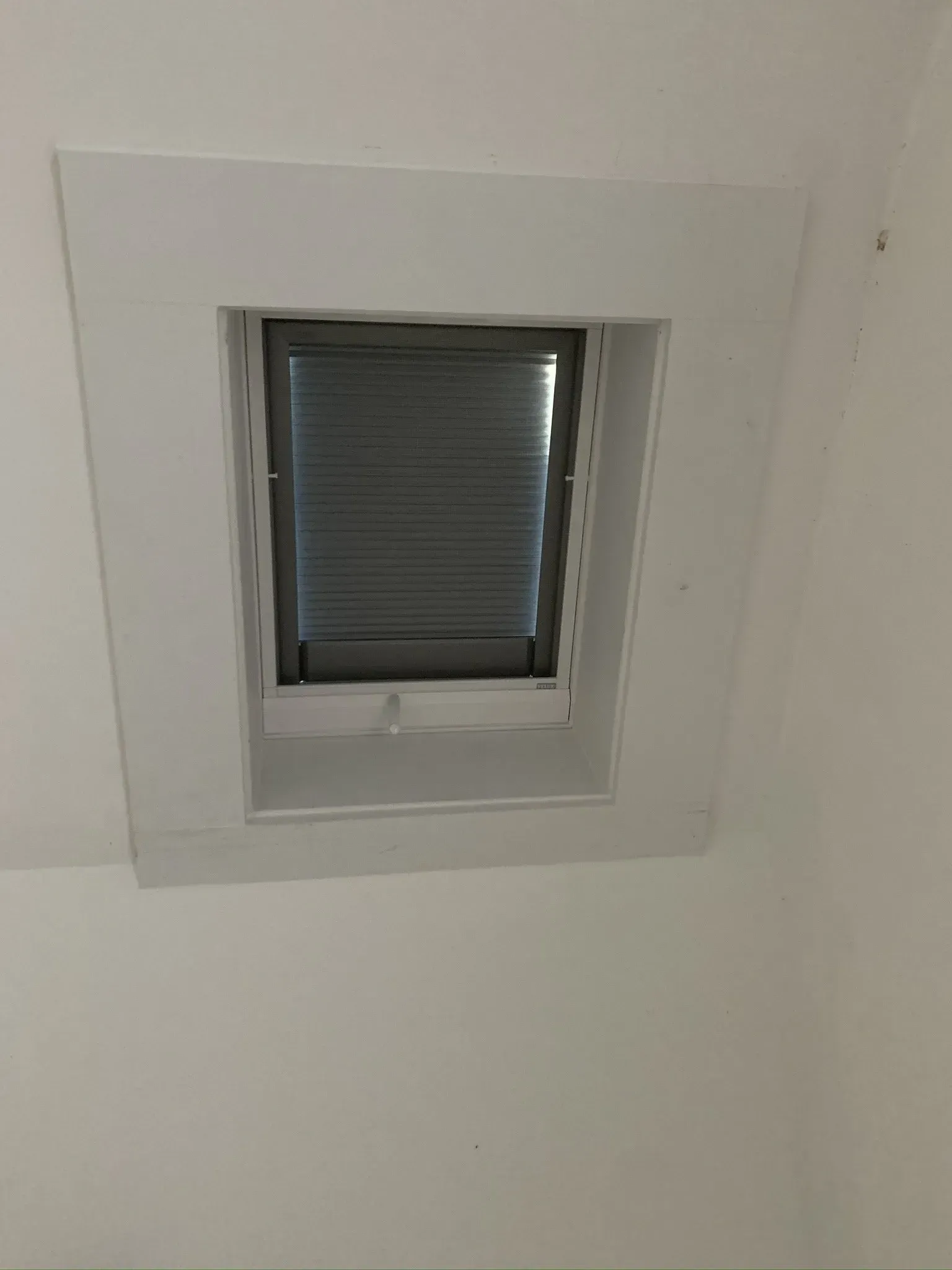 White square skylight with gray blinds, set in a white ceiling.