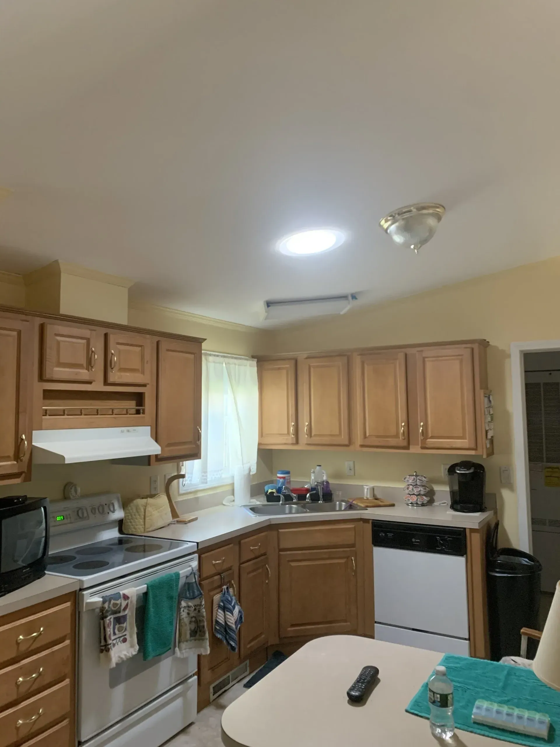Kitchen with wooden cabinets, appliances, and a skylight.