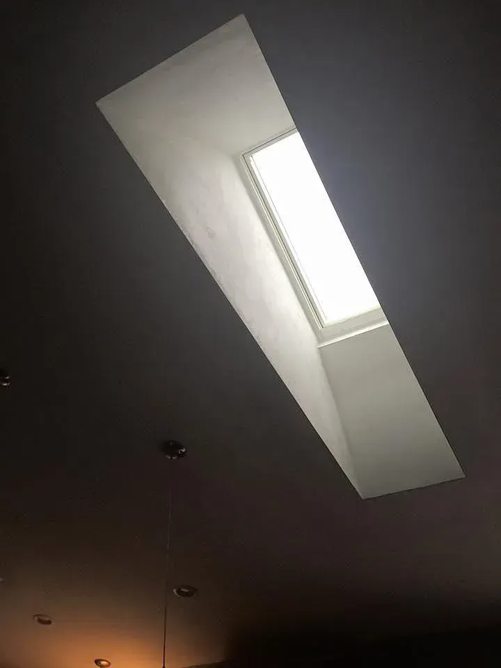 Skylight in a ceiling, angled, rectangular shape, with a bright light source.