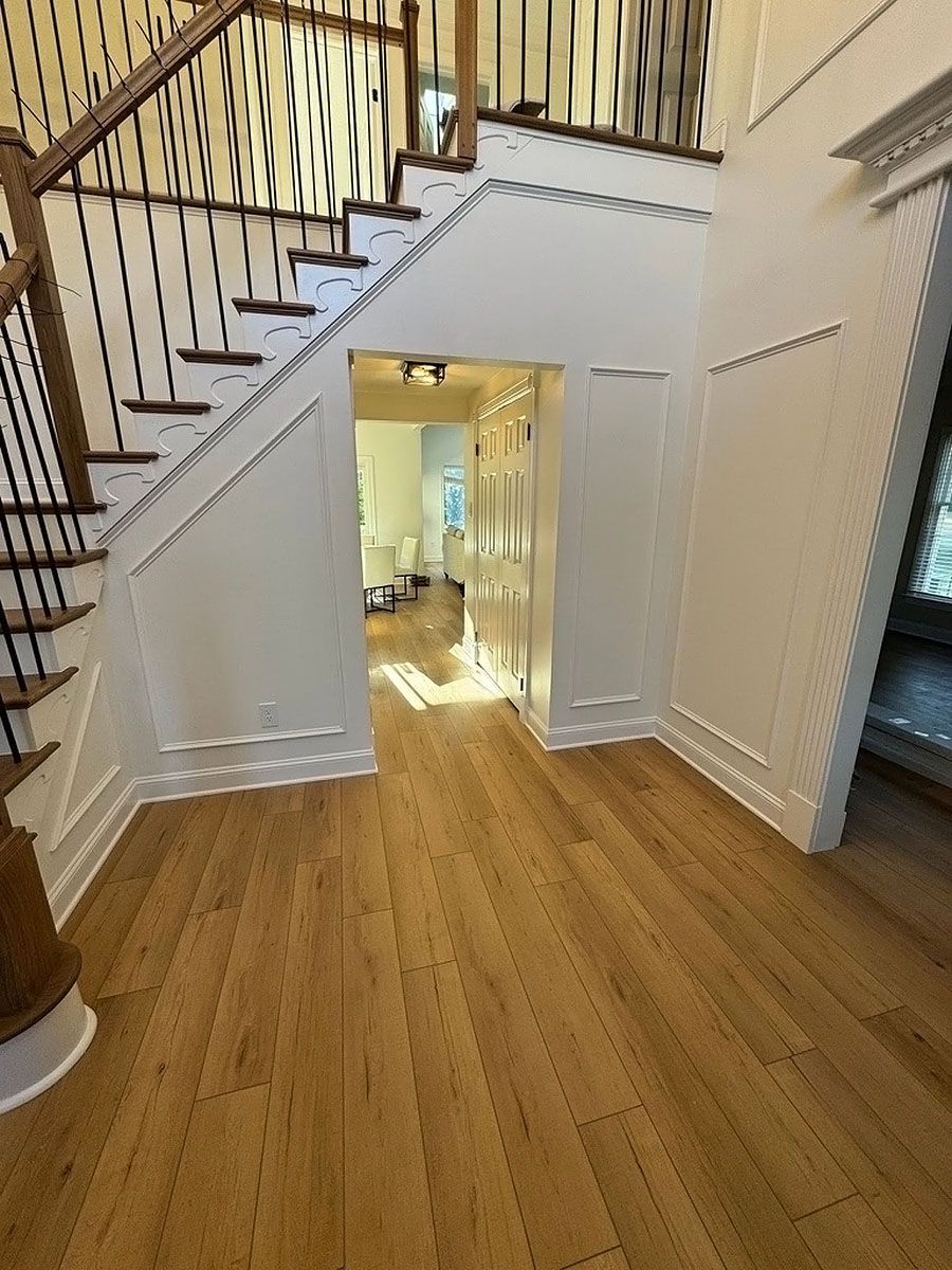 Wooden staircase and hallway in a bright home with white walls and railings