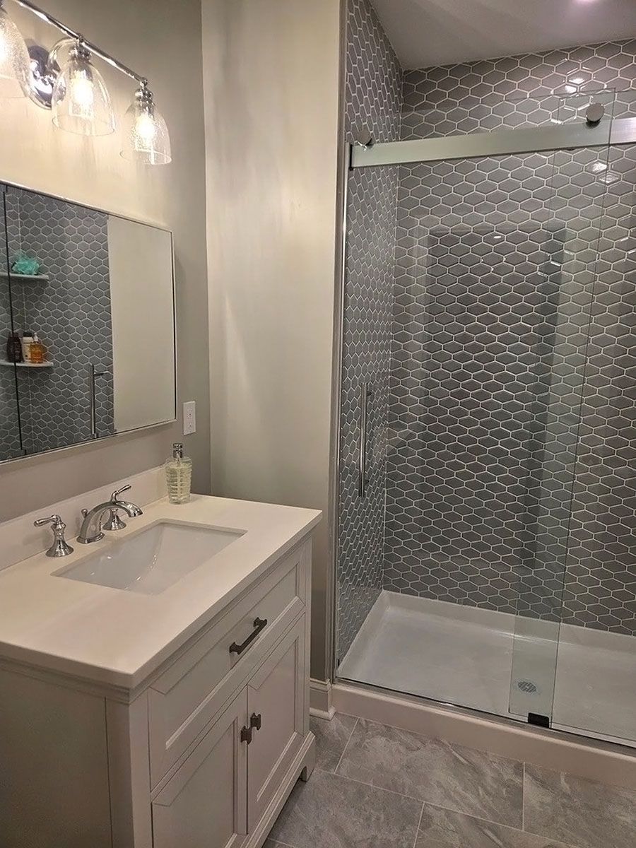Modern bathroom with white vanity, large mirror, and glass-enclosed shower.