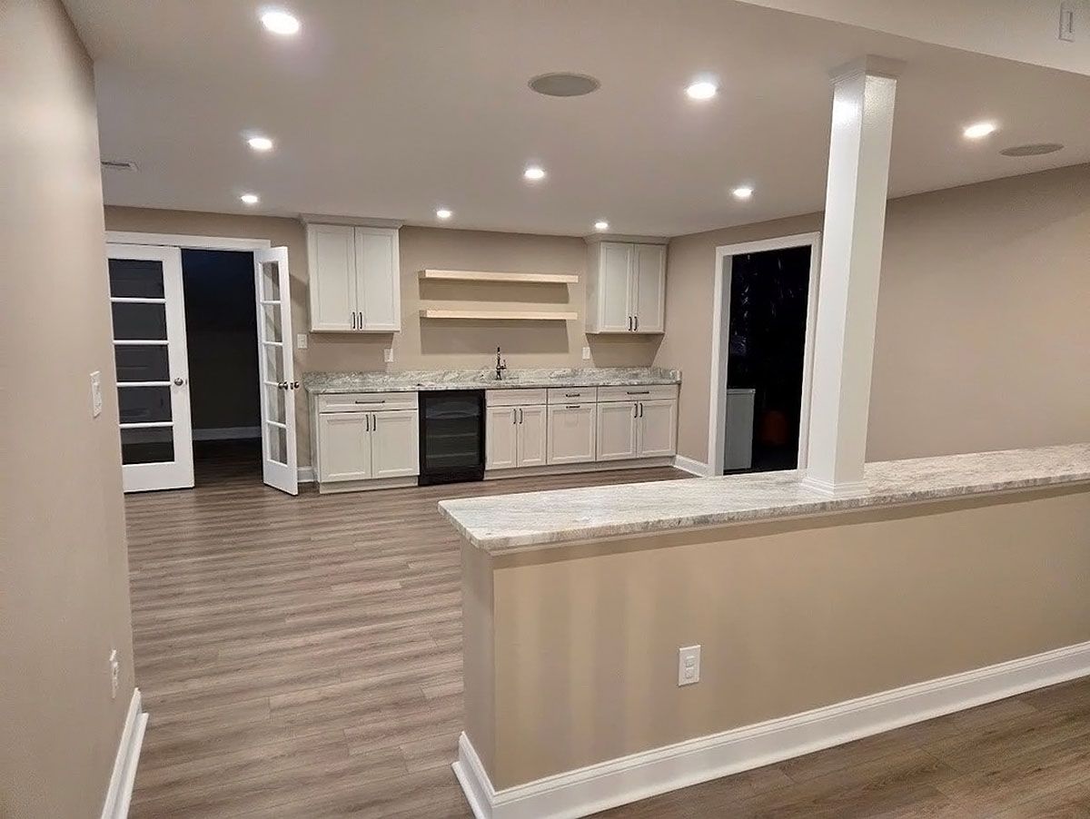 Open-plan kitchen and living area with light cabinets, island, recessed lighting, and wood-look flooring