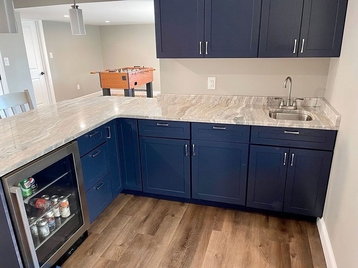 Blue kitchen cabinets with granite countertops and wood flooring, viewed from a corner.