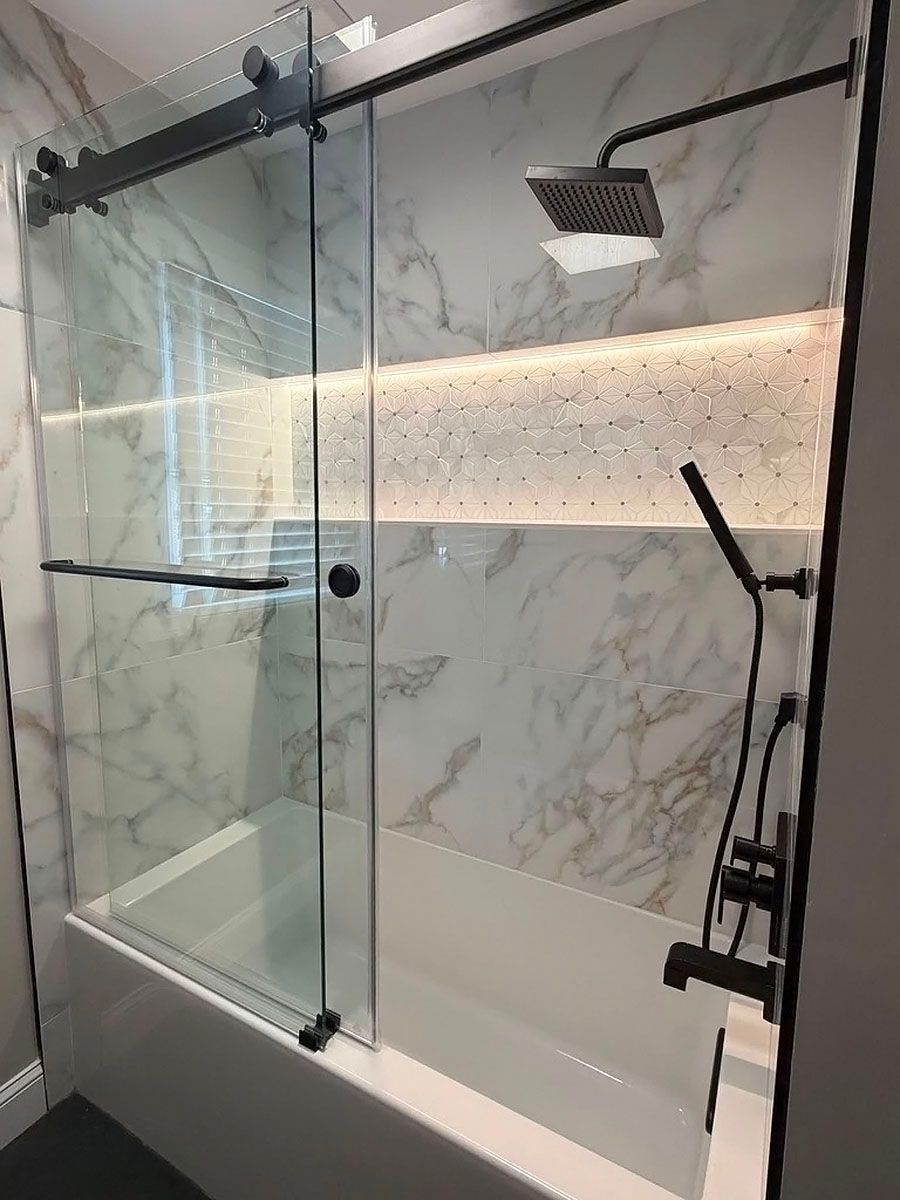 Modern glass shower with marble tile, rainfall showerhead, and black fixtures