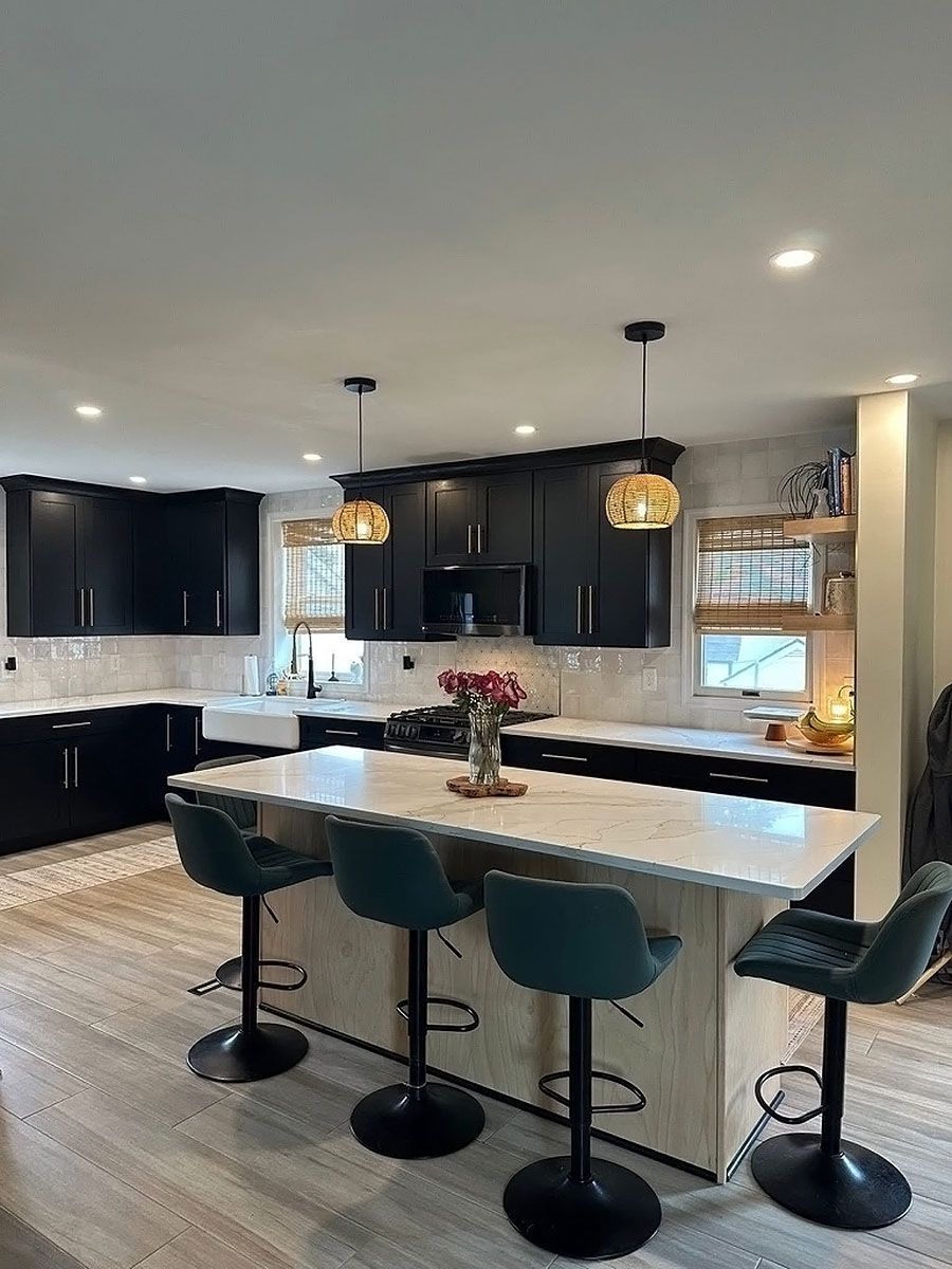 Modern kitchen with dark cabinets, white island, and four green bar stools under pendant lights