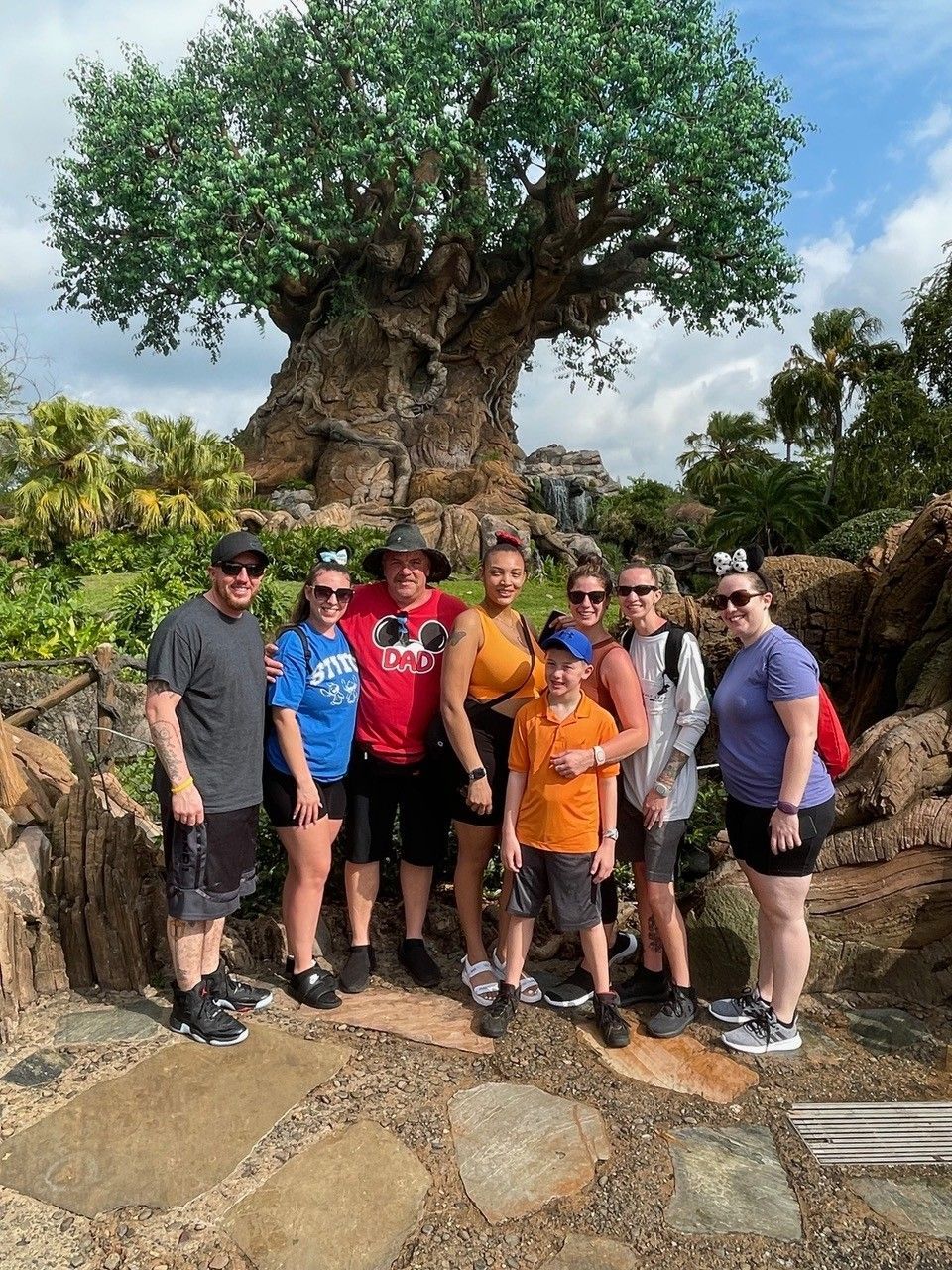 A group of people are posing for a picture in front of a tree of life.