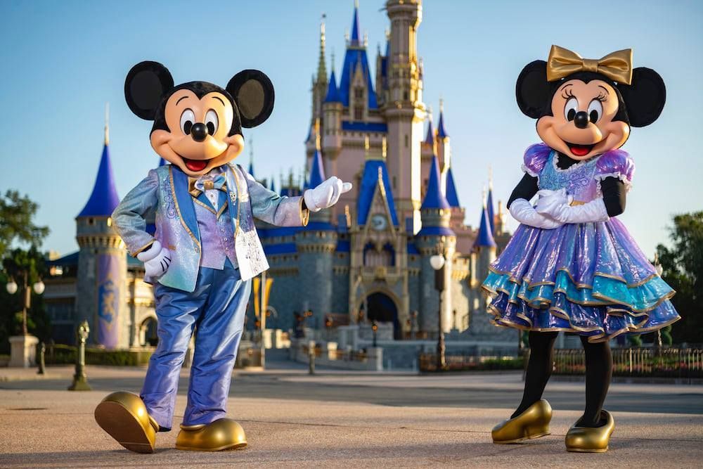 Mickey mouse and minnie mouse are standing in front of a castle.