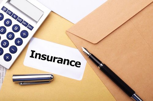 Insurance paperwork with calculator, pen, and envelope on a desk