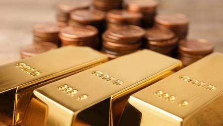 Three gold bars are sitting on top of a pile of coins.