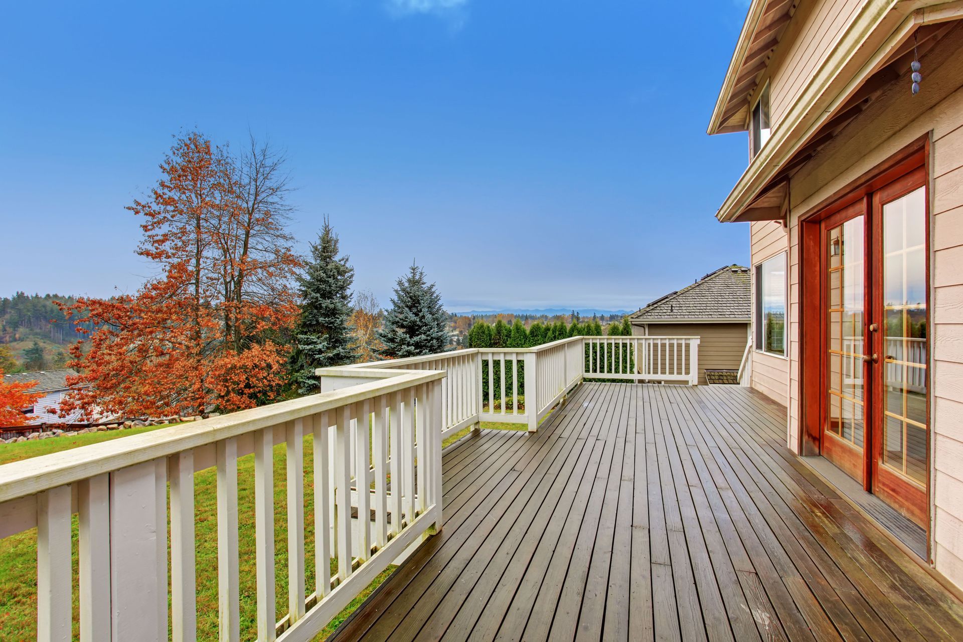 Wooden deck on a house with a view of trees and a blue sky