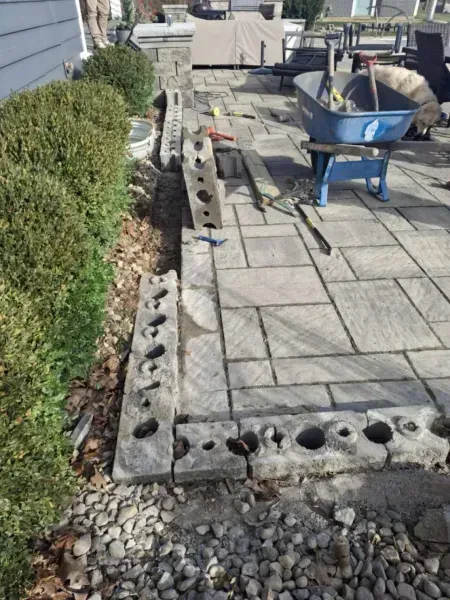 Patio construction with stone pavers, border blocks, and wheelbarrow.