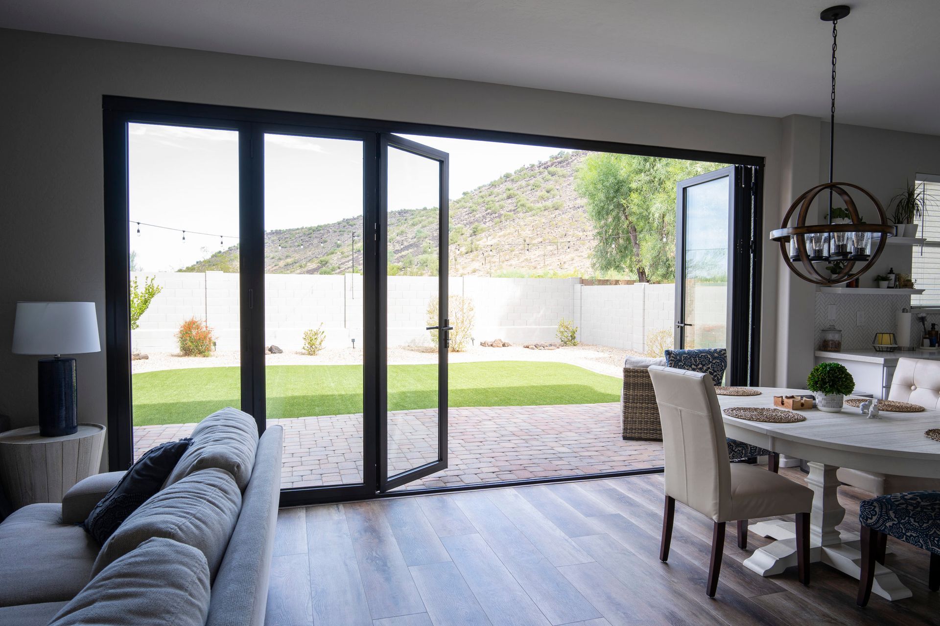 Living room with open glass doors to a backyard with lawn and a mountain view.