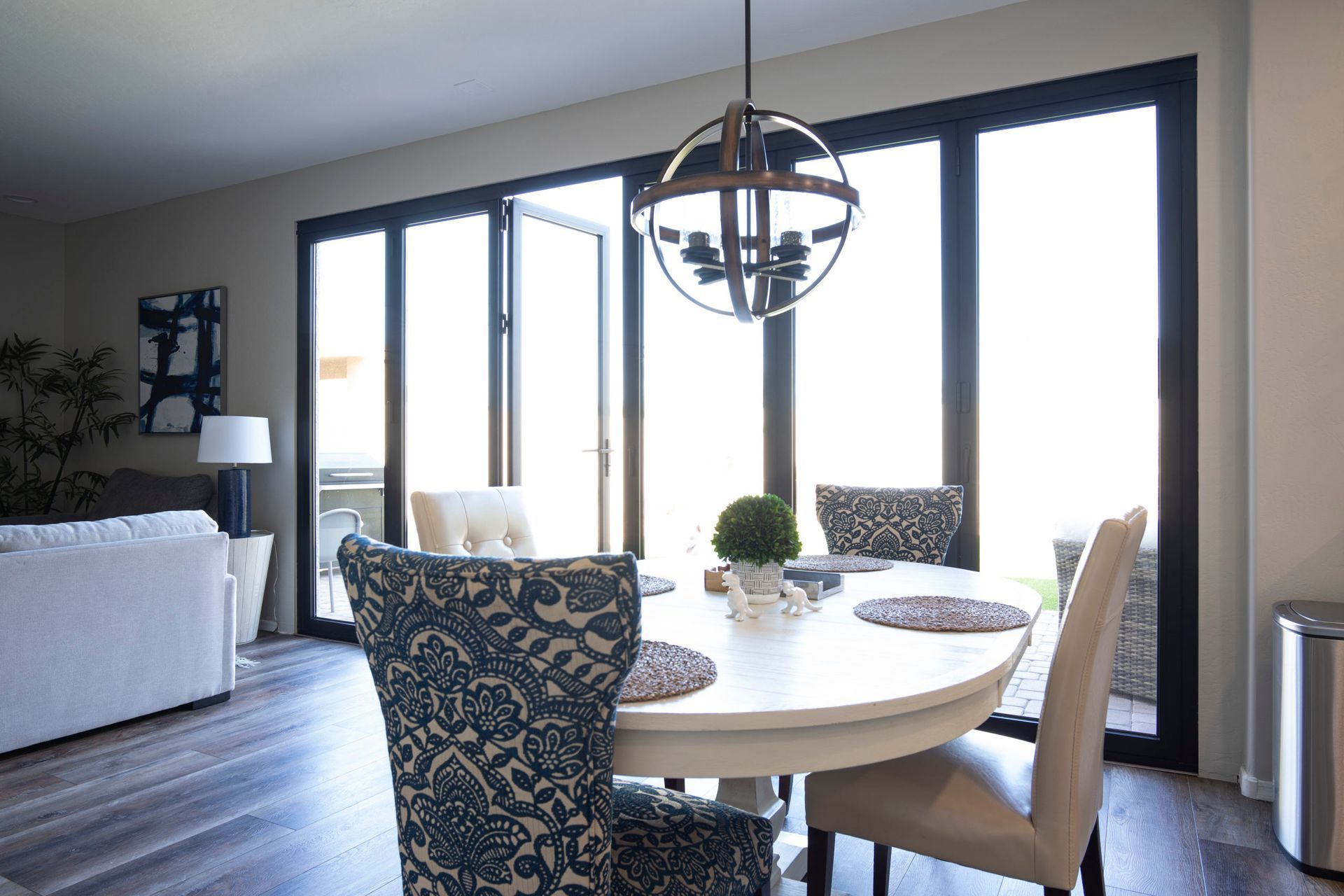 Dining area with round table, chairs, and open patio doors. Bright with globe light.
