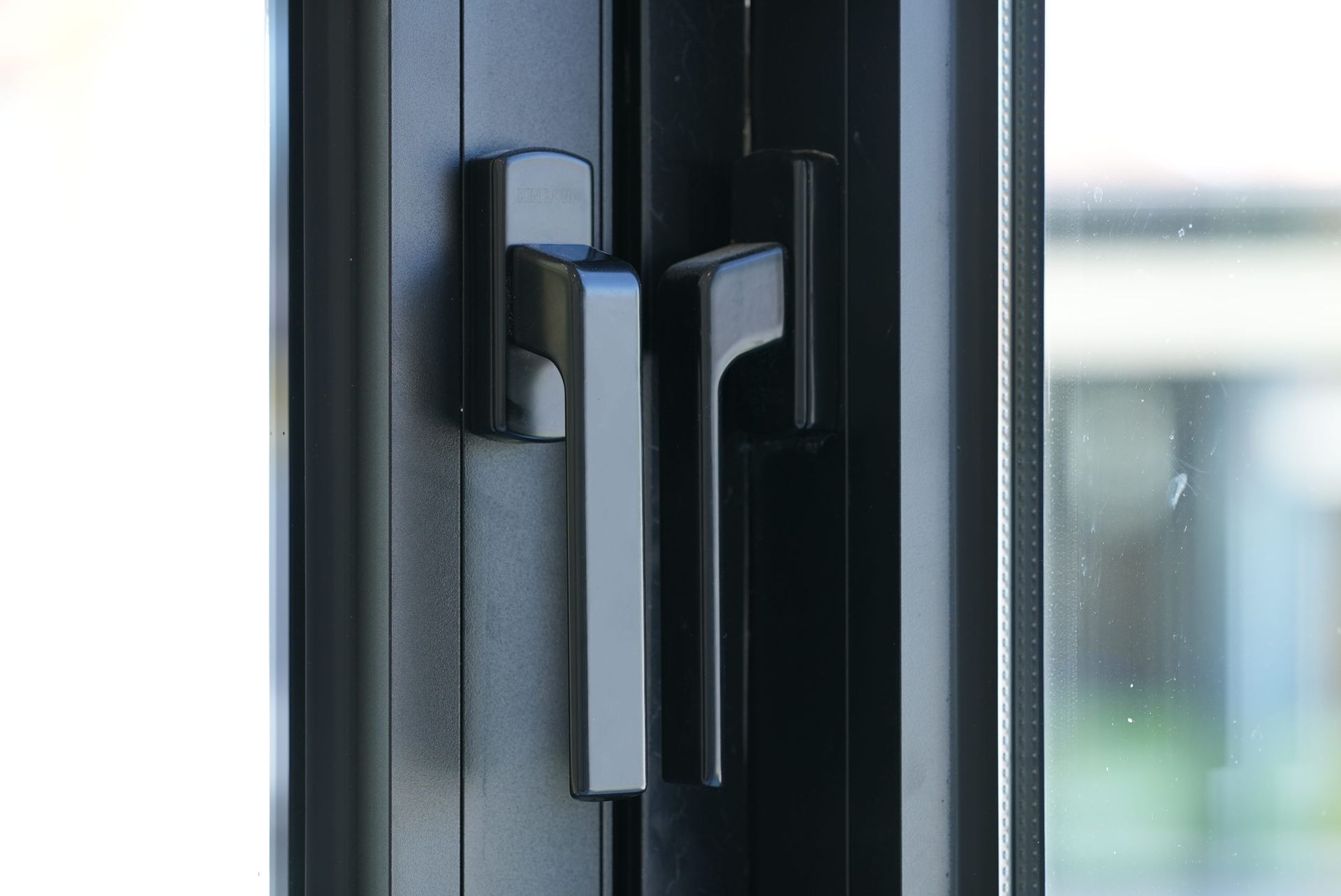 Black window handles, close-up. One vertical, one horizontal.