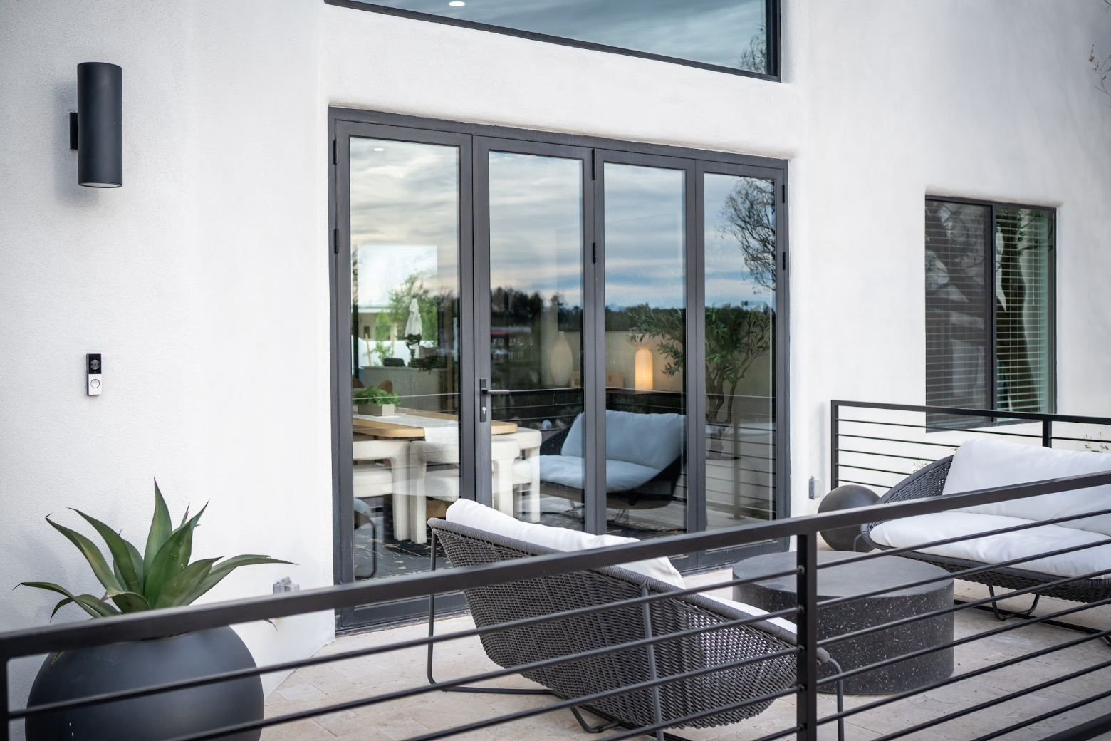 Modern patio with glass doors, black lounge chairs, and white exterior walls