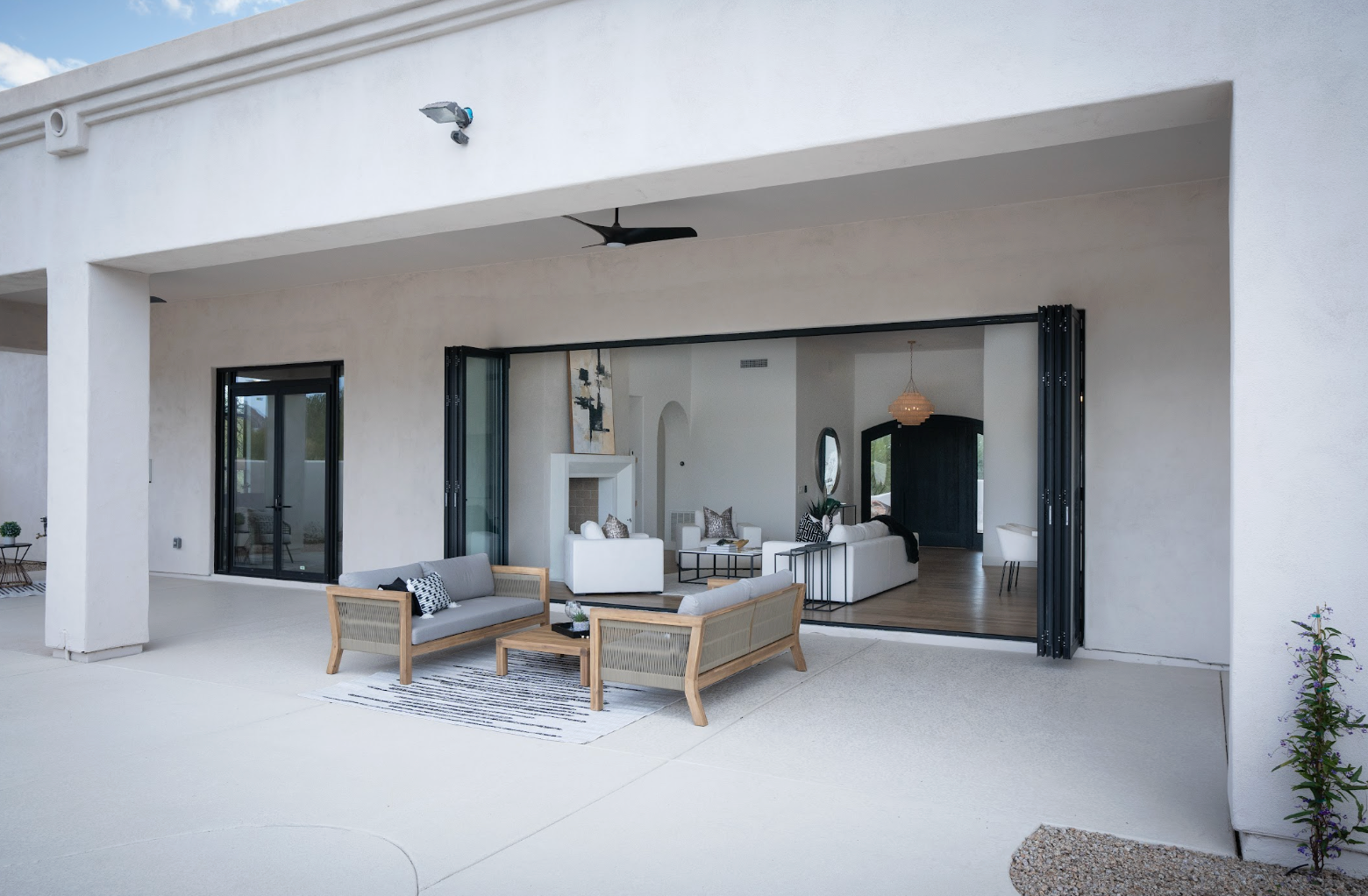 Covered patio with wicker seating and open sliding glass doors to a modern living room