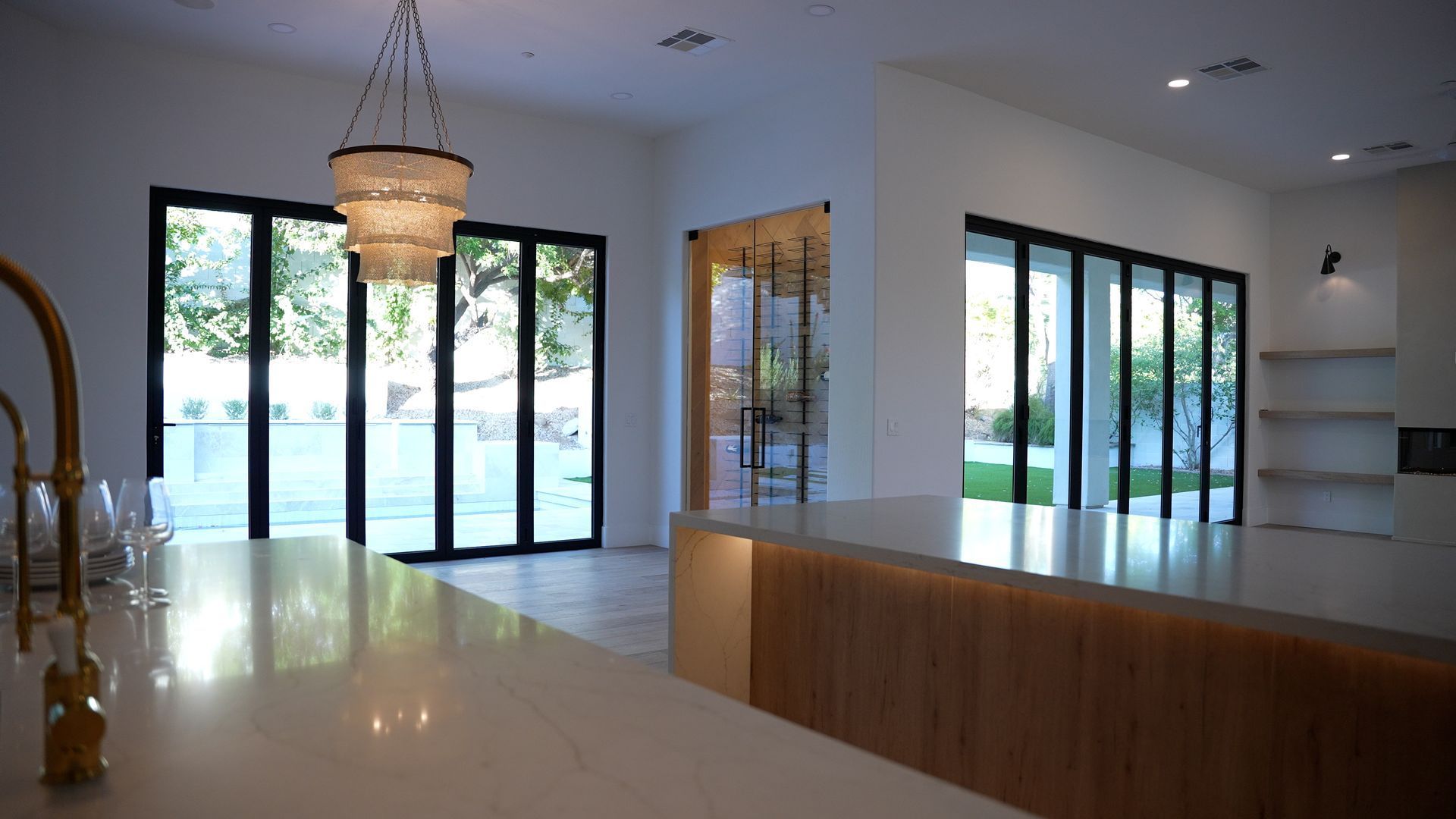 Bright modern empty room with large glass doors, chandelier, and glossy floors