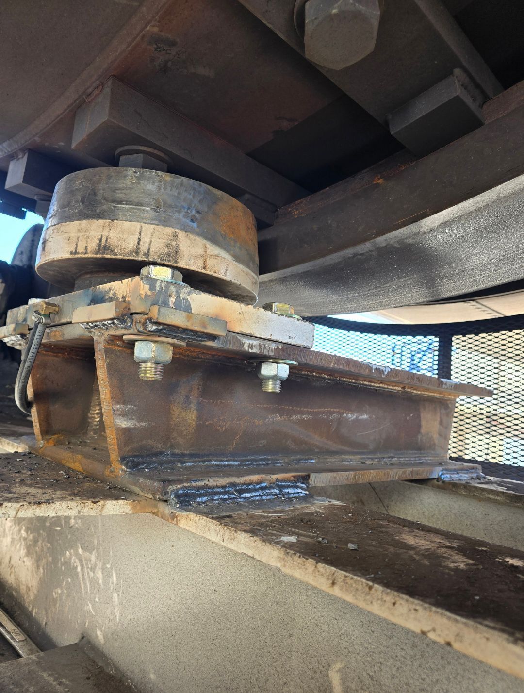 Rusty industrial machine part mounted under equipment on a metal surface