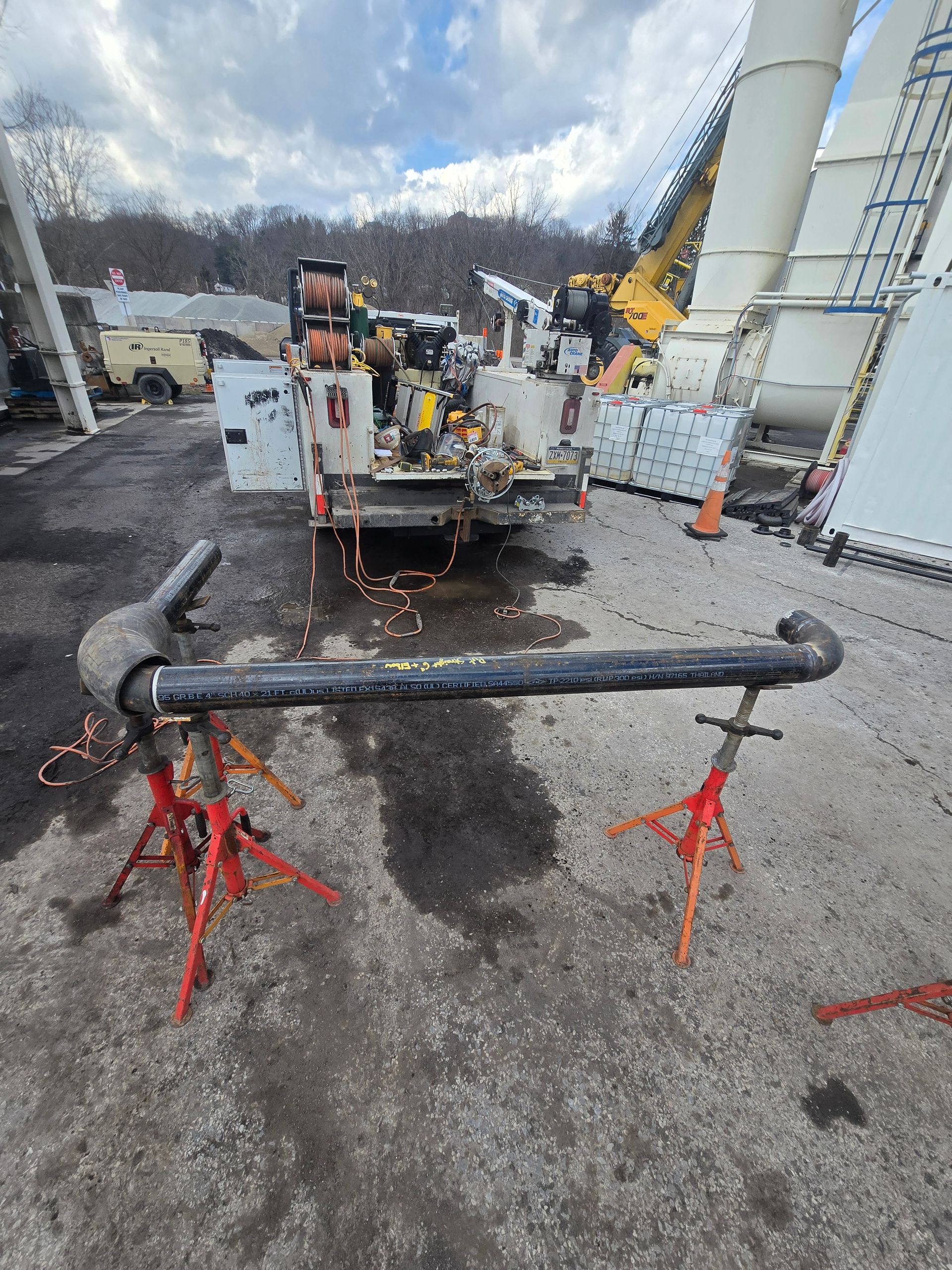 Black pipe on red stands in a wet industrial yard