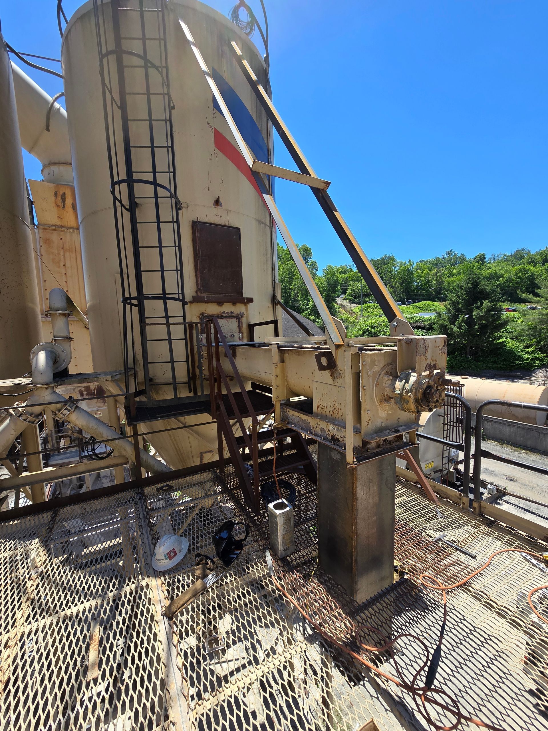 Industrial machinery and metal piping on a rooftop platform under a clear blue sky