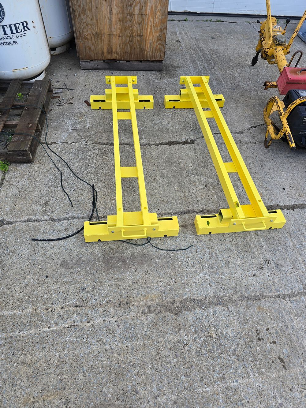 Two yellow metal ramps lying on a concrete floor in an industrial area.