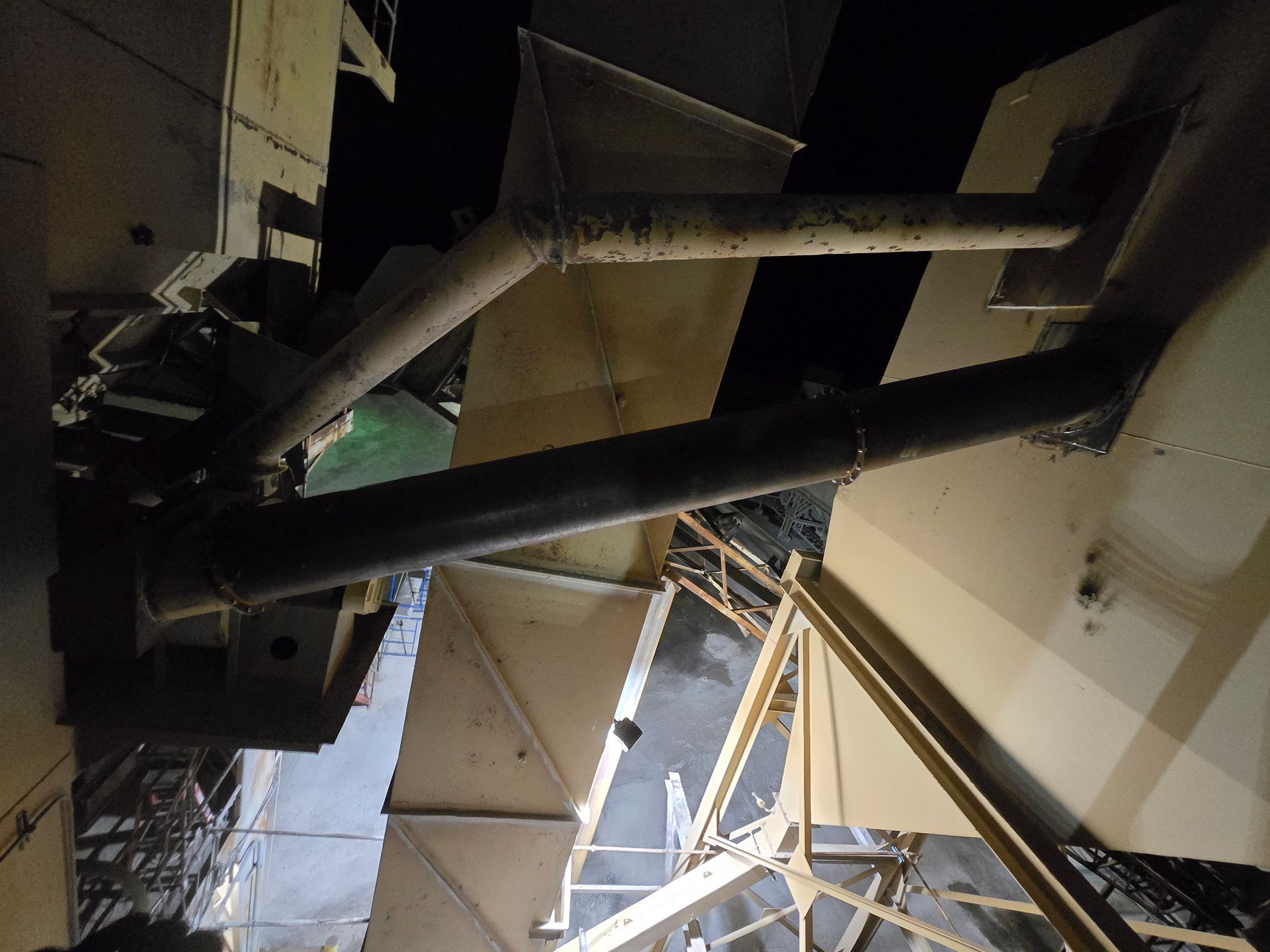 Close-up of black pipes and metal beams inside an industrial or construction structure.