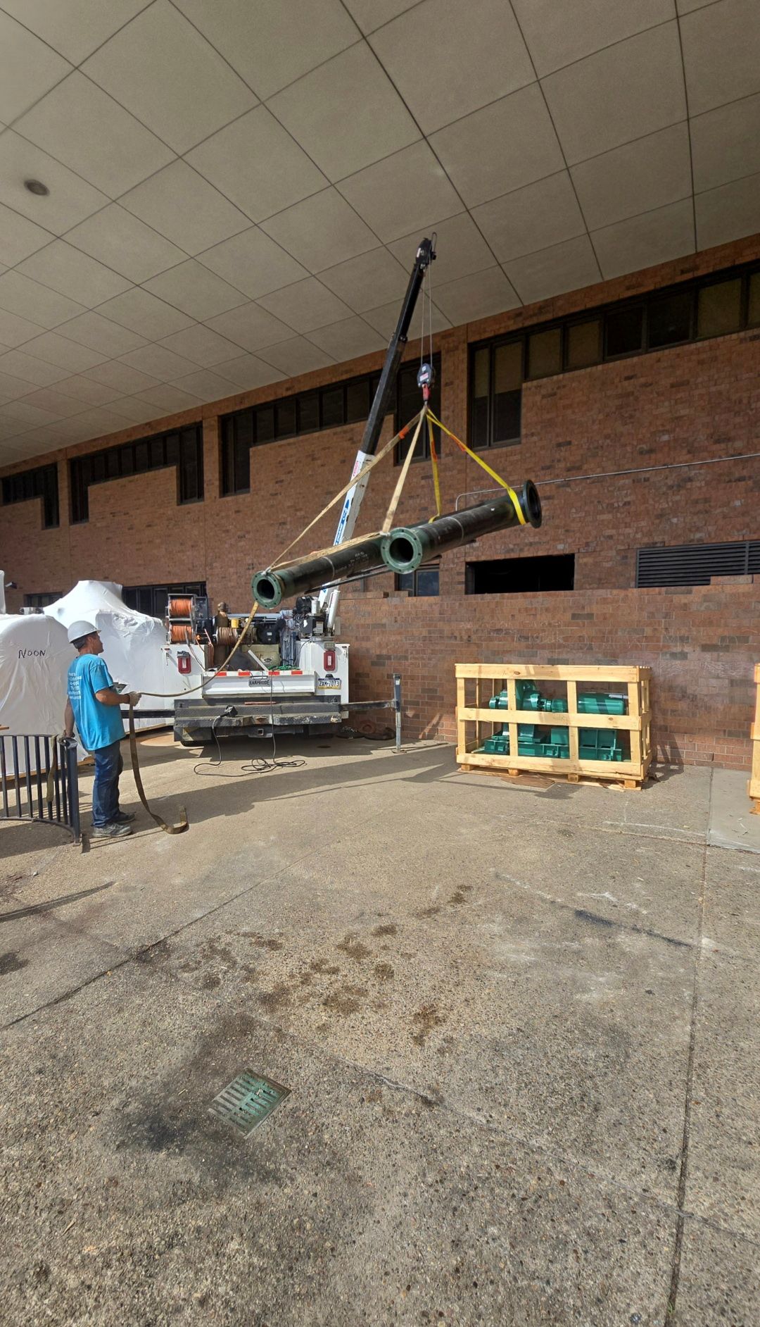 Crane lifting a metal pipe