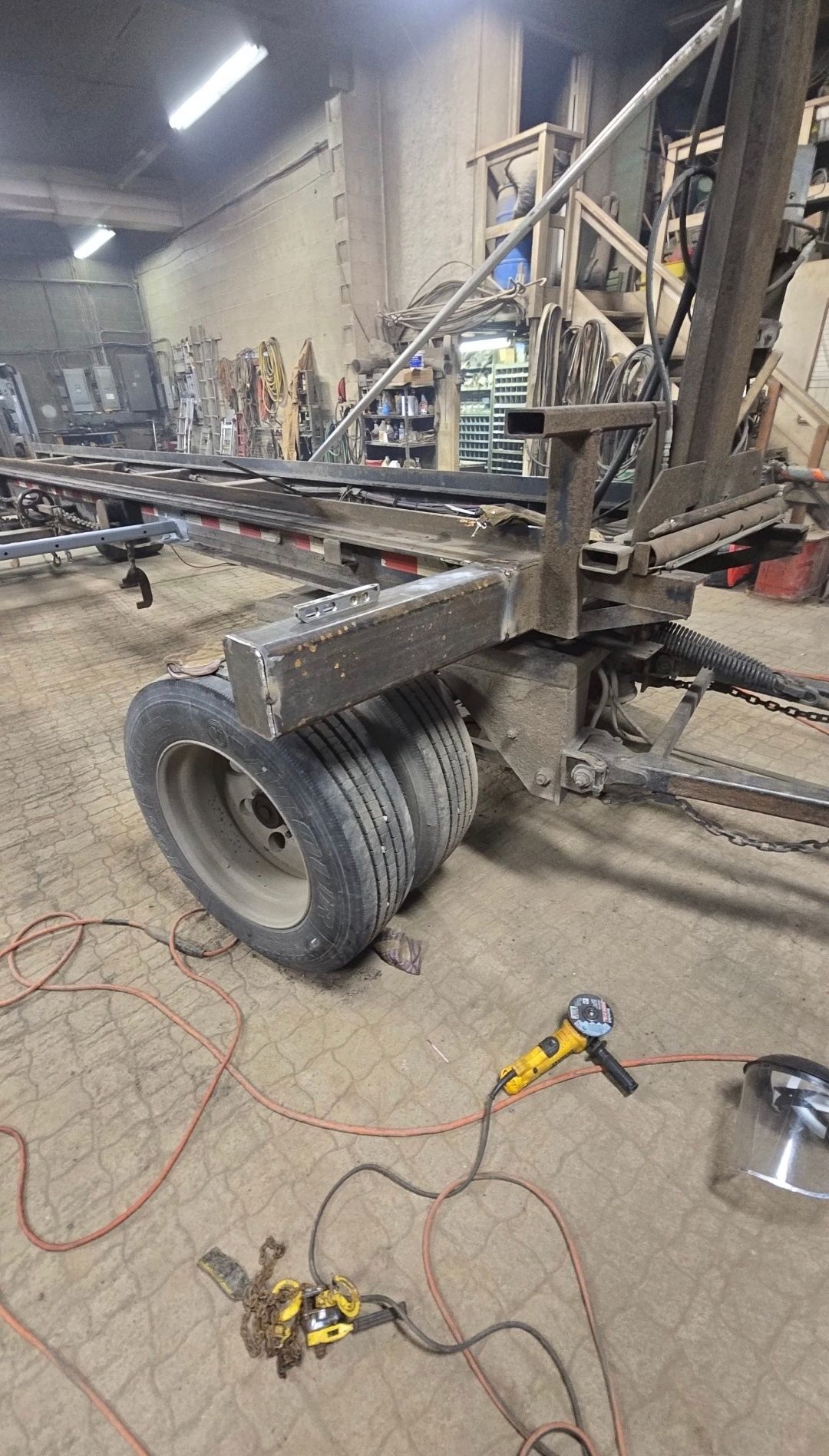 Workshop scene with a large wheeled metal frame, tools, and cables on a concrete floor