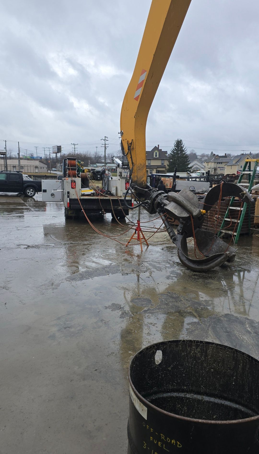 Yellow excavator arm at a muddy construction site