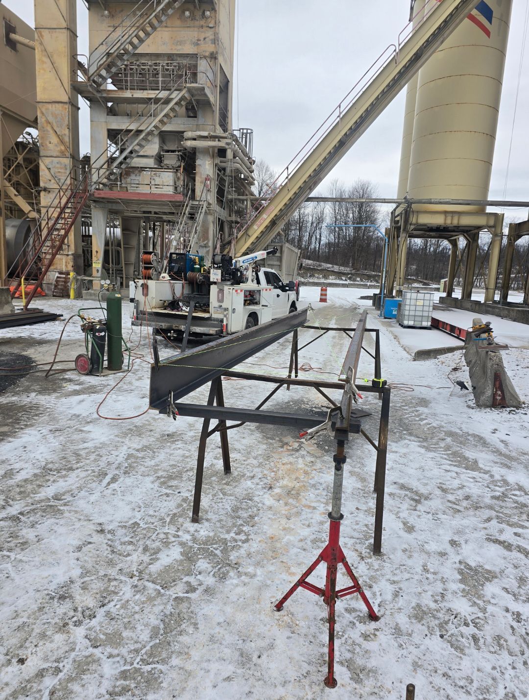 Industrial worksite with metal framework, crane, and large silo towers