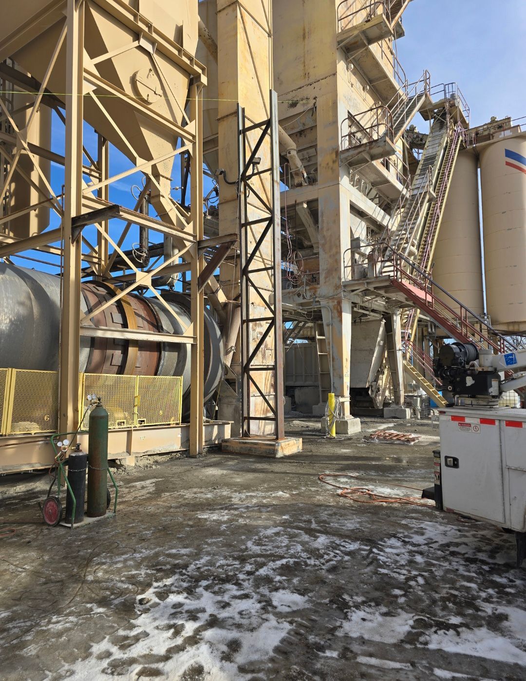 Damaged industrial plant with collapsed metal structure and debris on snowy ground