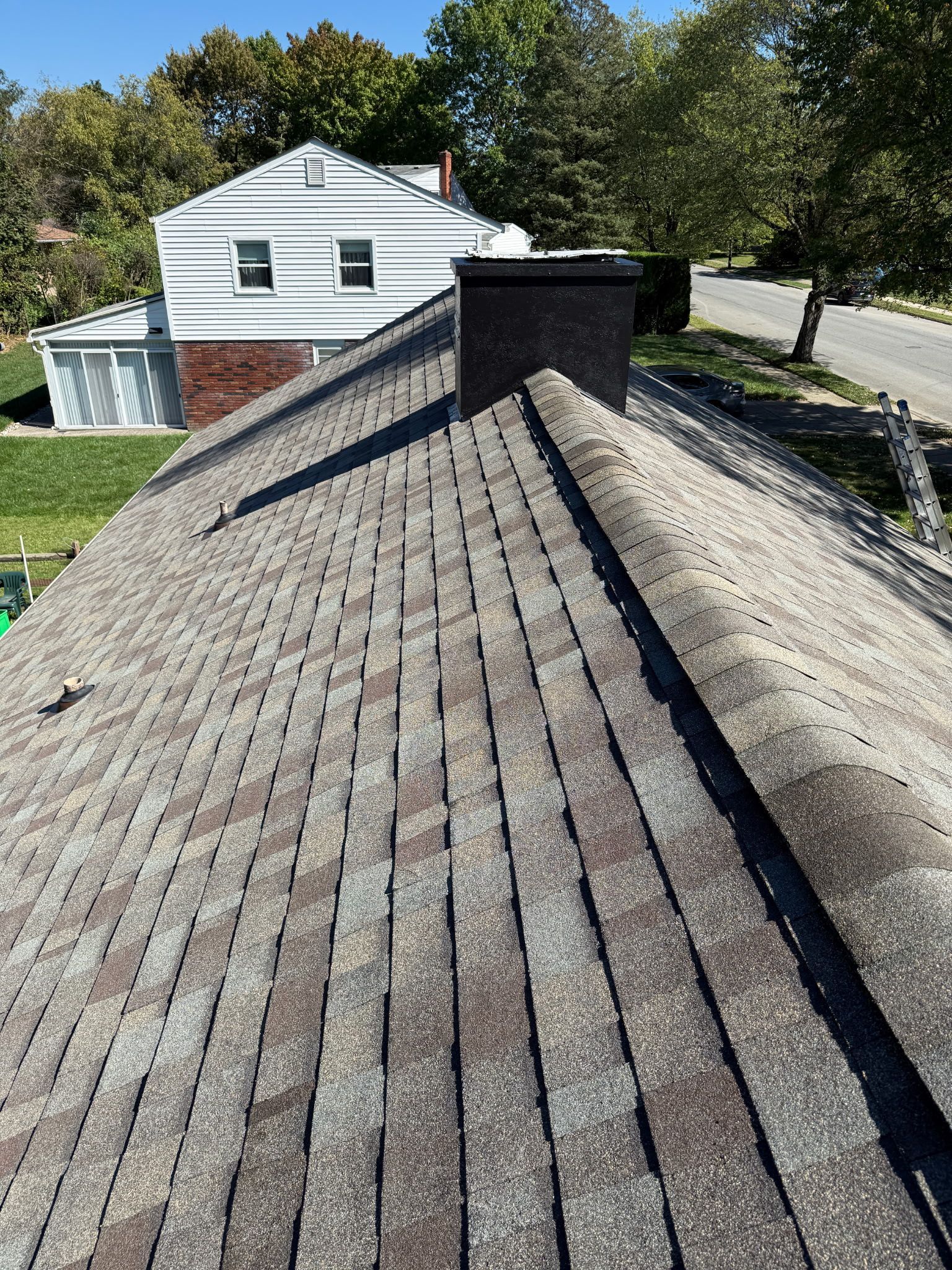 View of a weathered asphalt shingle roof with a dark chimney.