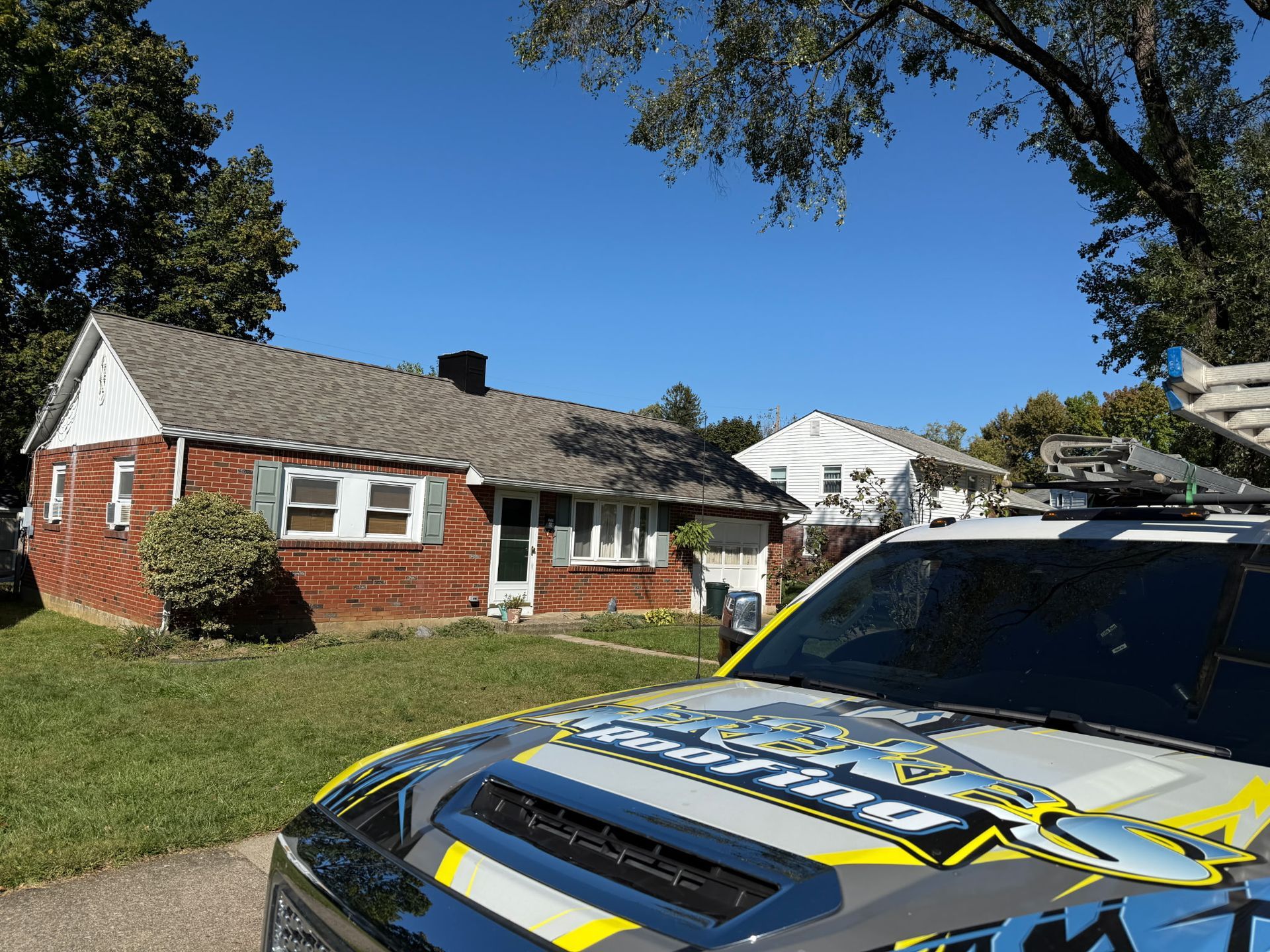 A red brick house with a police vehicle parked in front on a sunny day.